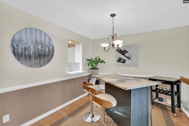 dining room with baseboards, a notable chandelier, and light wood-style floors