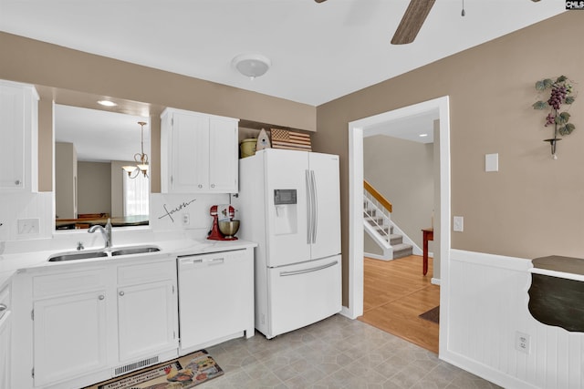 kitchen with white appliances, ceiling fan, light countertops, white cabinetry, and a sink