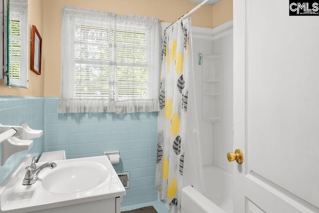 full bathroom with shower / bath combo with shower curtain, tile walls, wainscoting, and vanity