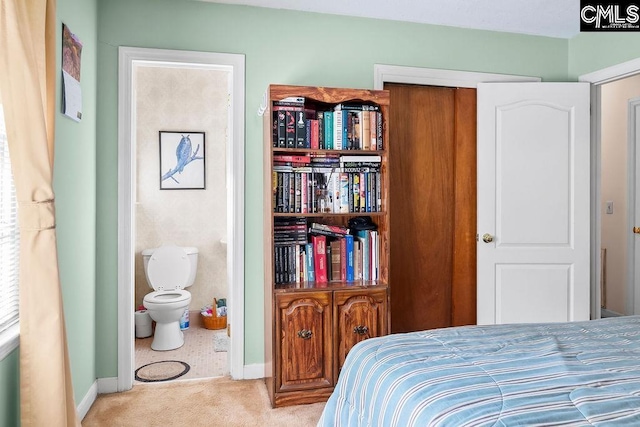 carpeted bedroom featuring baseboards and ensuite bathroom