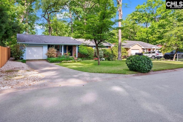 ranch-style home featuring an attached garage, fence, a front yard, and aphalt driveway