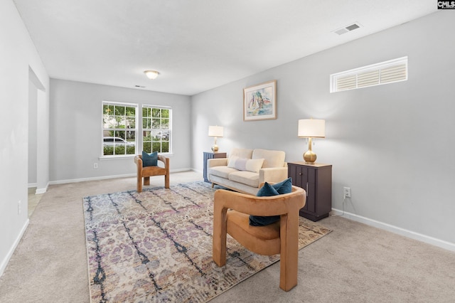 living area with baseboards, visible vents, and light carpet