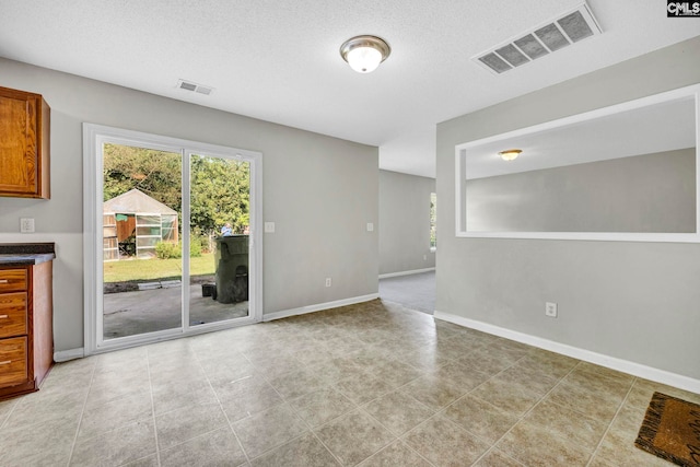 unfurnished room with baseboards, a textured ceiling, and visible vents