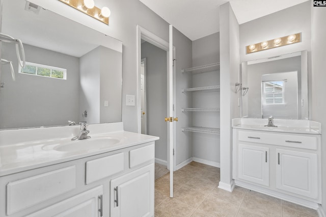 full bathroom with baseboards, two vanities, a sink, and tile patterned flooring