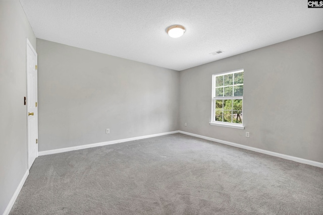 carpeted spare room featuring a textured ceiling, visible vents, and baseboards