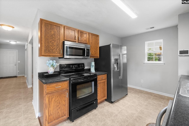 kitchen with dark countertops, appliances with stainless steel finishes, brown cabinetry, baseboards, and visible vents