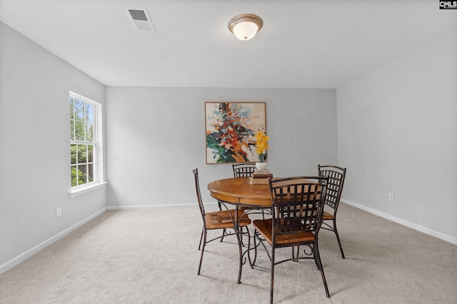 dining room featuring visible vents, baseboards, and light carpet