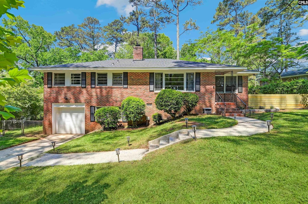 view of front of home with driveway, a front yard, brick siding, fence, and an attached garage