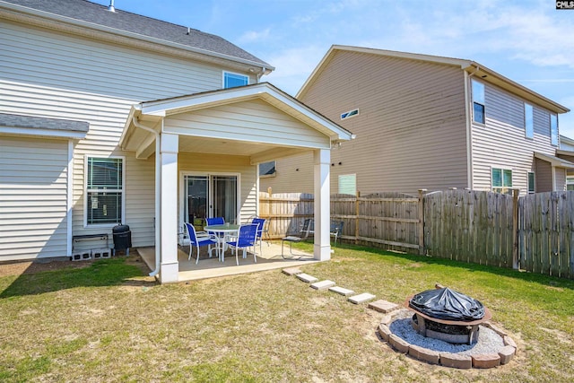 rear view of house with a fenced backyard, a patio, a yard, and an outdoor fire pit