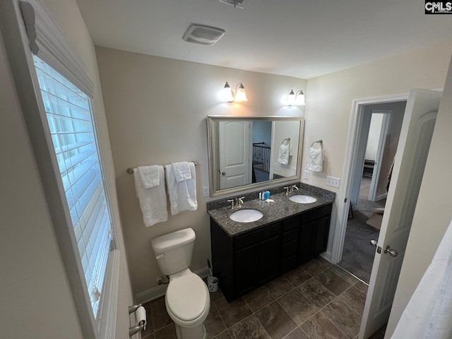 full bath with a sink, toilet, double vanity, and visible vents
