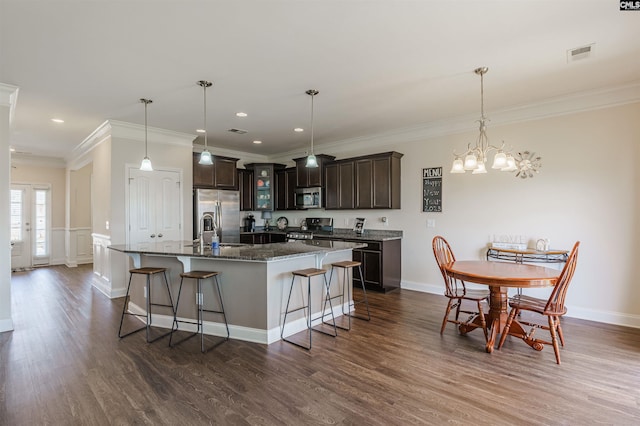 kitchen featuring visible vents, dark brown cabinetry, a breakfast bar, dark wood-type flooring, and appliances with stainless steel finishes