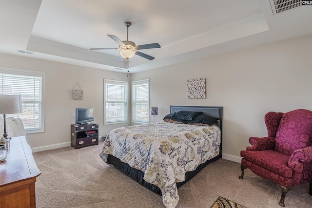 bedroom featuring visible vents, a tray ceiling, and light carpet