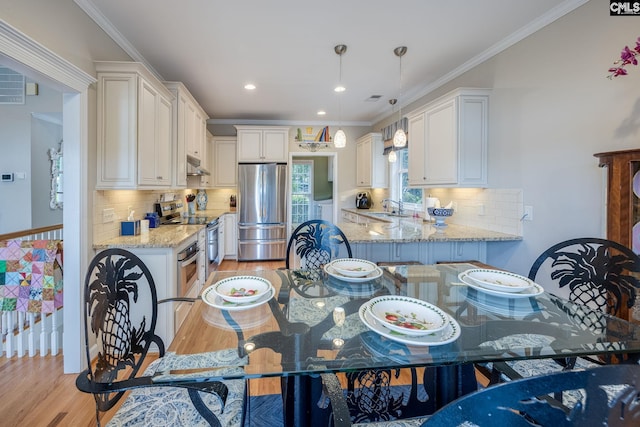 dining space with recessed lighting, ornamental molding, and light wood-style floors