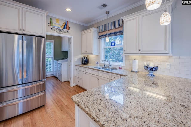 kitchen with visible vents, a sink, white cabinets, freestanding refrigerator, and washer and dryer