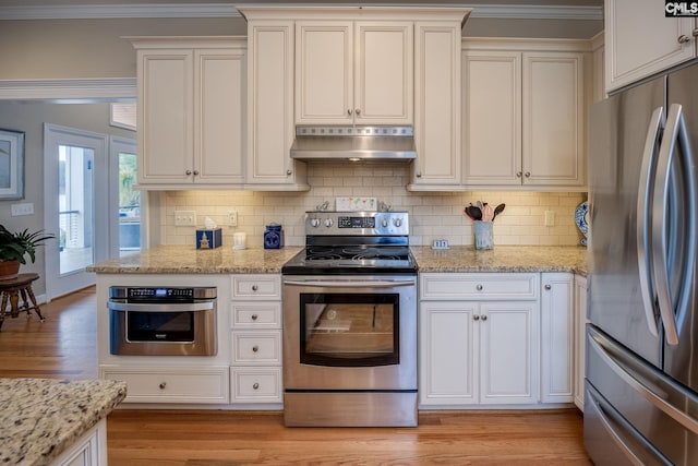 kitchen featuring light wood-style floors, under cabinet range hood, light stone counters, backsplash, and stainless steel appliances