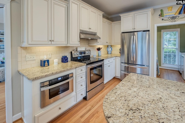kitchen with light wood-style floors, appliances with stainless steel finishes, under cabinet range hood, and tasteful backsplash