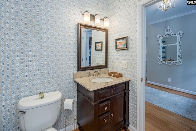 bathroom with crown molding, wood finished floors, baseboards, vanity, and toilet