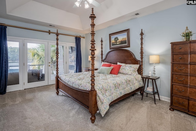 carpeted bedroom featuring access to outside, a tray ceiling, and visible vents