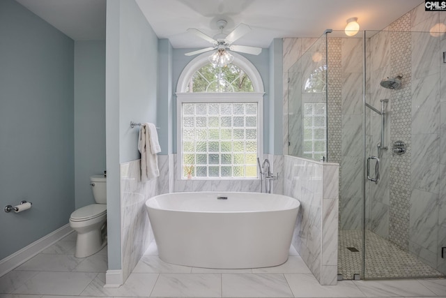 bathroom with a freestanding tub, toilet, tile walls, a ceiling fan, and a stall shower