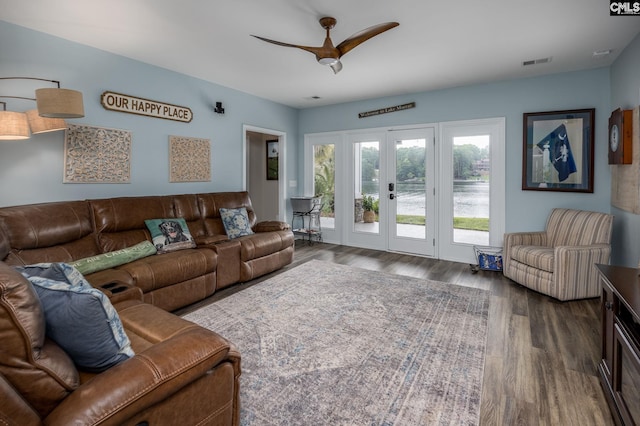 living area featuring ceiling fan, french doors, visible vents, wood finished floors, and a water view