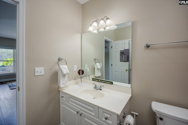 half bathroom with vanity, toilet, and wood finished floors