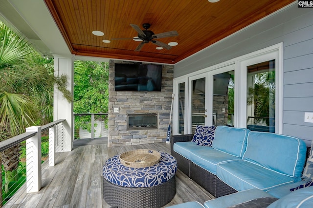 wooden deck featuring ceiling fan and an outdoor living space with a fireplace