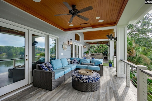 wooden terrace with an outdoor hangout area, a ceiling fan, french doors, and a water view