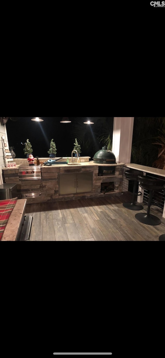 deck at twilight featuring exterior kitchen and a grill