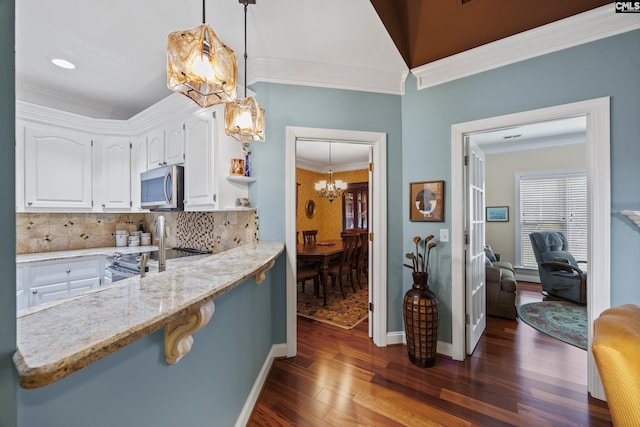 kitchen featuring crown molding, dark wood-style flooring, a chandelier, white cabinetry, and stainless steel microwave