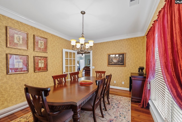 dining area with visible vents, crown molding, wood finished floors, a chandelier, and wallpapered walls