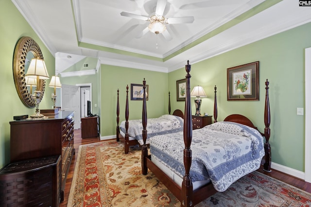bedroom featuring a raised ceiling, baseboards, ornamental molding, and wood finished floors