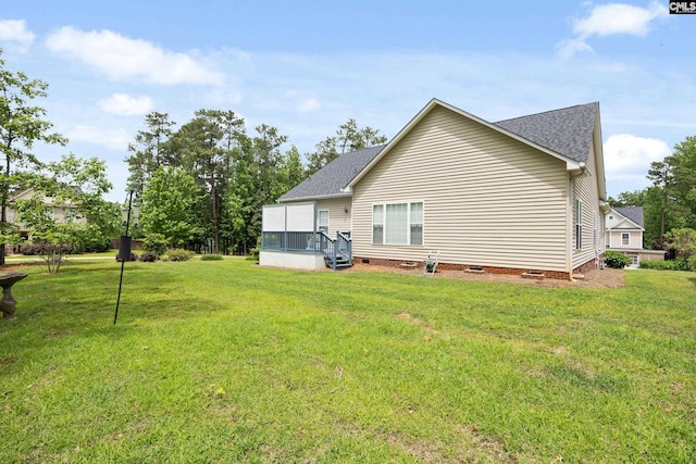 rear view of property with a shingled roof, a yard, and crawl space