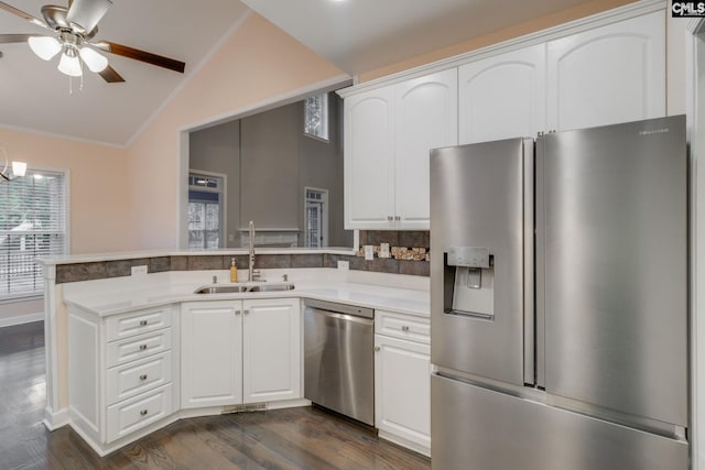 kitchen with a peninsula, lofted ceiling, dark wood-style floors, a sink, and stainless steel appliances