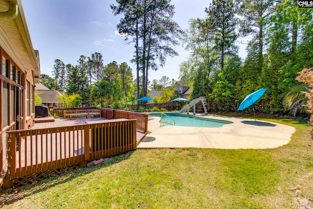 view of pool featuring a wooden deck, a fenced in pool, a fenced backyard, a yard, and a water slide