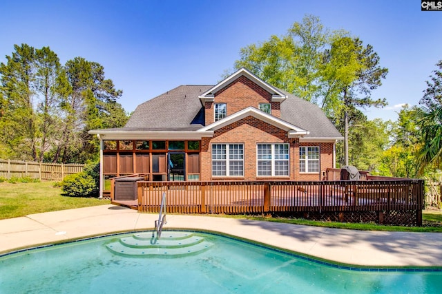rear view of property featuring brick siding, a fenced in pool, fence, and a sunroom