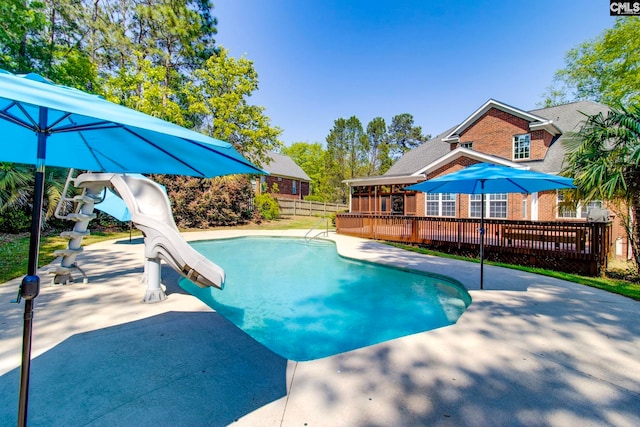 view of pool featuring a deck, a patio area, fence, a fenced in pool, and a water slide