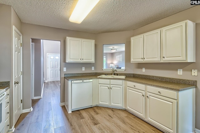 kitchen featuring white dishwasher, dark countertops, light wood-style floors, and a sink