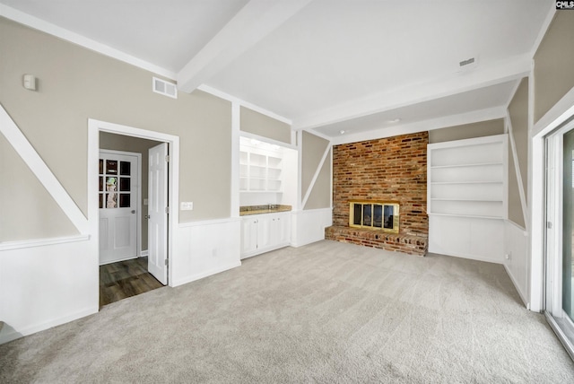 unfurnished living room featuring built in features, carpet, beam ceiling, and visible vents