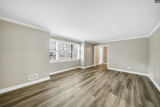 unfurnished room with visible vents, baseboards, crown molding, and wood finished floors