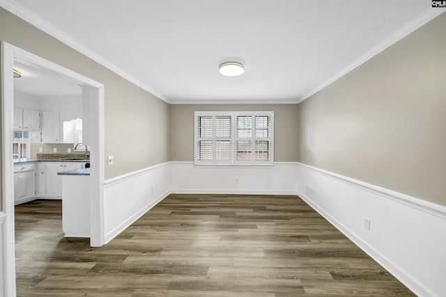 unfurnished dining area with dark wood finished floors, ornamental molding, a sink, and visible vents