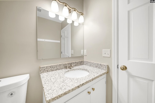 half bathroom featuring toilet, visible vents, and vanity