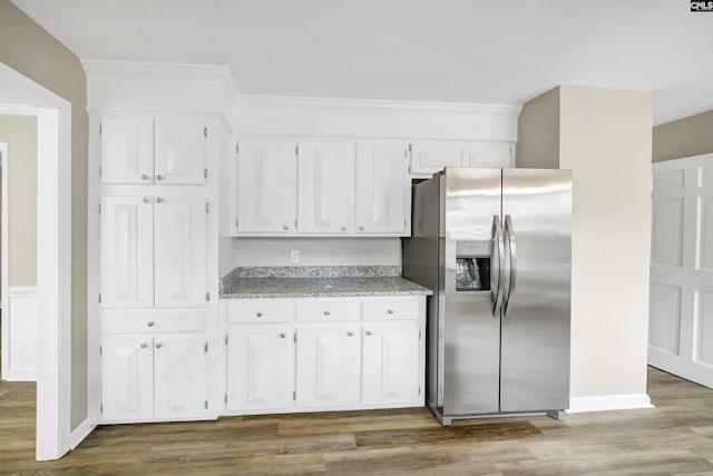 kitchen with wood finished floors, baseboards, white cabinetry, stainless steel fridge with ice dispenser, and light stone counters