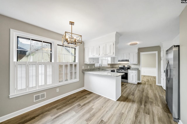 kitchen featuring a sink, stainless steel appliances, a peninsula, under cabinet range hood, and visible vents