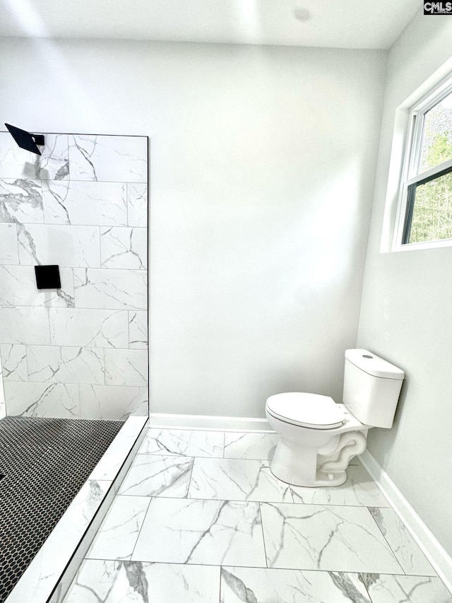 full bath featuring toilet, baseboards, tiled shower, and marble finish floor