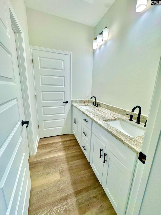 full bathroom with double vanity, a sink, and wood finished floors