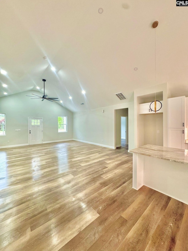 unfurnished living room with visible vents, light wood-style floors, baseboards, a ceiling fan, and vaulted ceiling