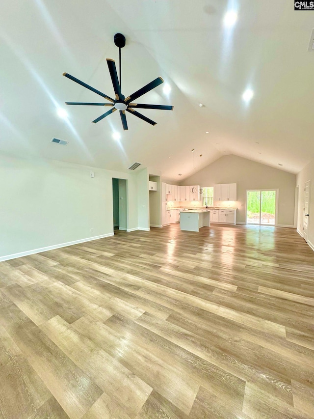 unfurnished living room with visible vents, a ceiling fan, light wood-type flooring, and lofted ceiling