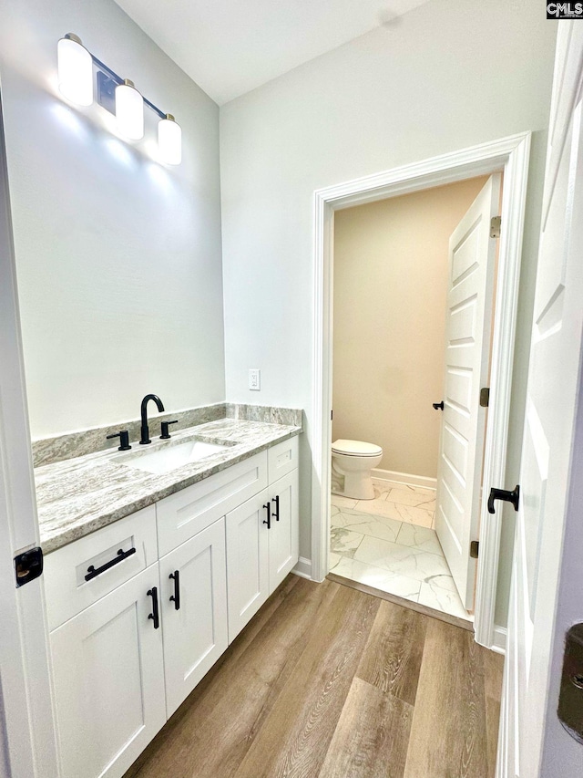 bathroom featuring toilet, baseboards, marble finish floor, and vanity
