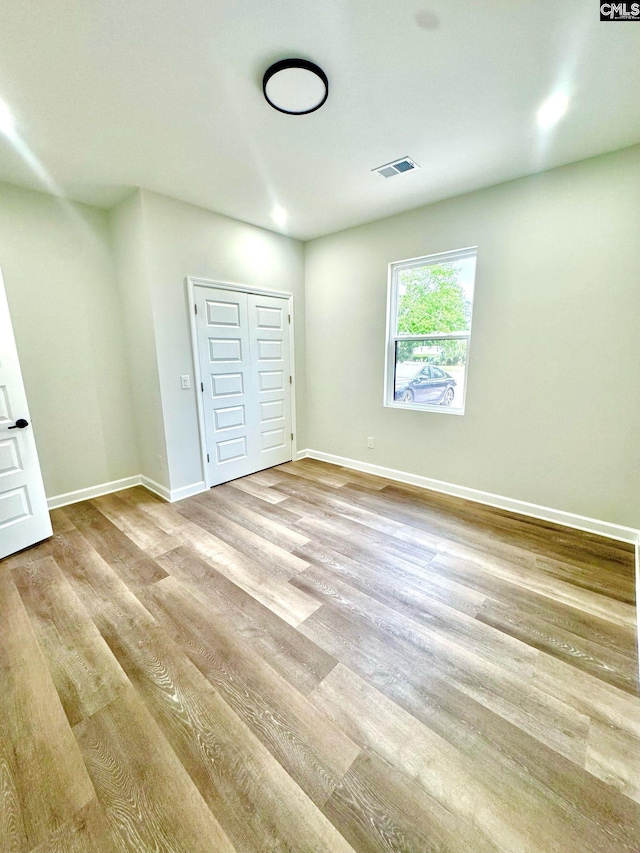 unfurnished bedroom with visible vents, light wood-style floors, baseboards, and a closet