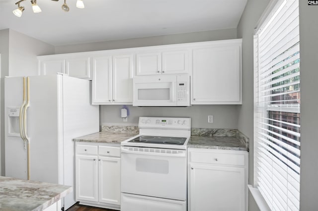 kitchen with light countertops, white cabinets, and white appliances
